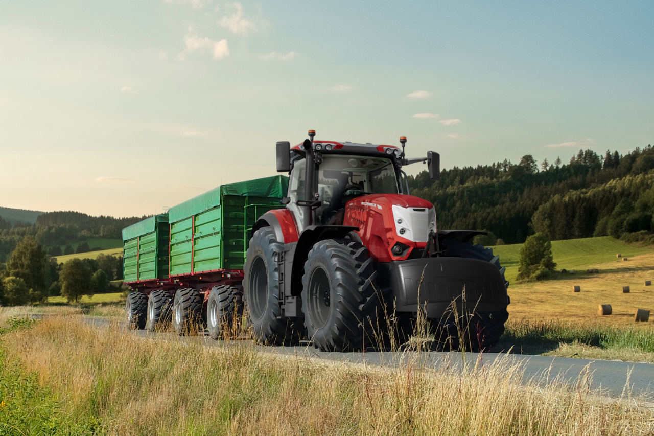 picture of a red McCormick X8 tractor with a loader wagon stopped in the middle of a road
